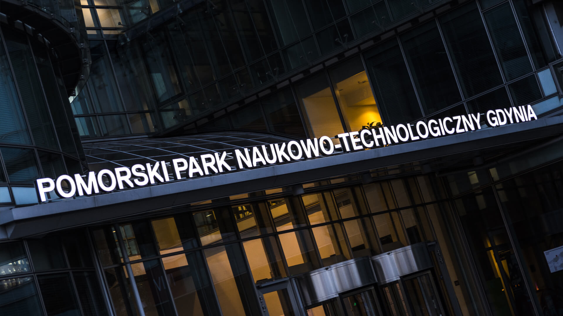 Parc scientifique et technologique de Poméranie à Gdynia  - pomeranian-science-and-technology-park-spatial-lettering-sub-illuminated-led-litres-over-entry-roof-lettering-white-lettering-on-steel-logo